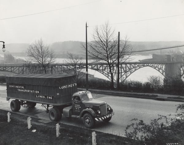 1944 International semi-truck (tractor-trailer) on a road with a hazy view of a bridge