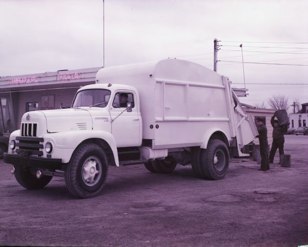 1954 International garbage collection truck parked beside a restaurant
